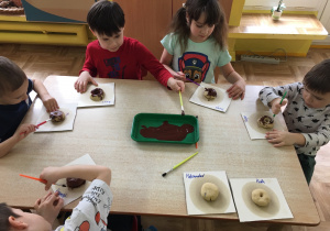 dzieci malują brązową farbą pączki z masy solnej